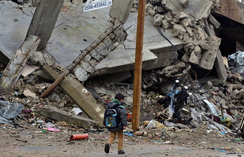 epa04647609 A Palestinian school boy walks past a destroyed house in al Shejaeiya neighbourhood in the east of Gaza City, 04 March 2015.  EPA/MOHAMMED SABER